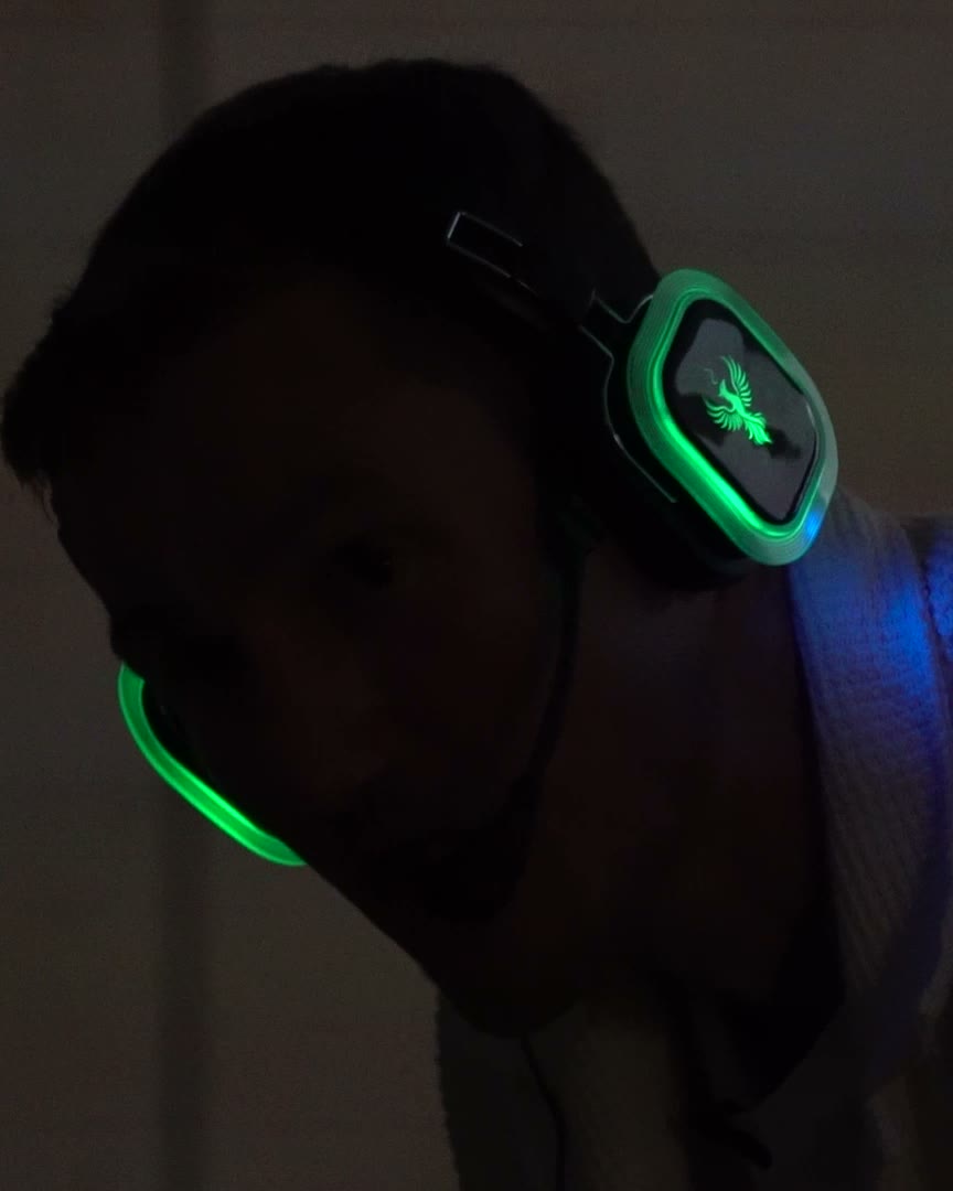 Someone at a Come Home evening wearing glowing green wireless headphones in a low-lit room.